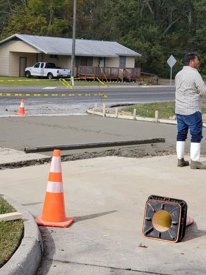 Worker finishing fresh concrete beside a street